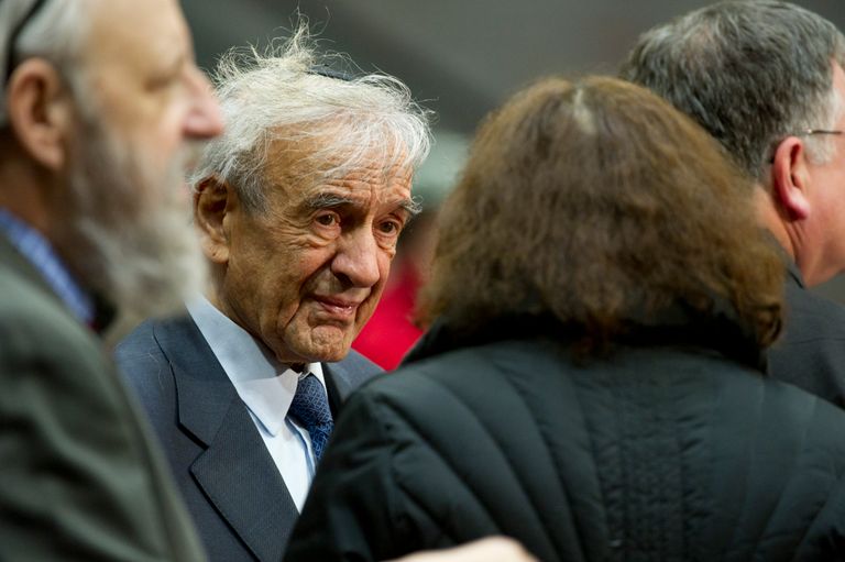 Elie Wiesel pictured between two other individuals, not clearly visible