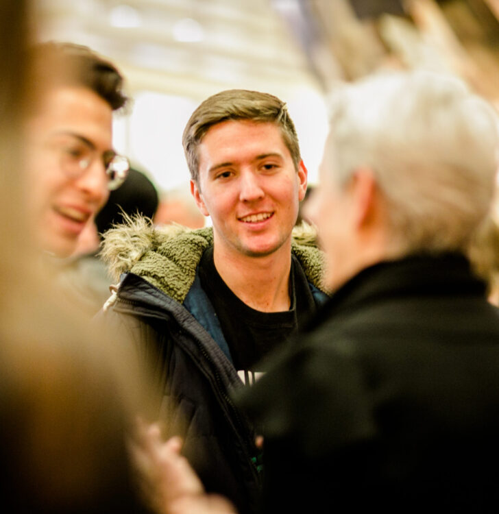 Two young men speaking with a professor