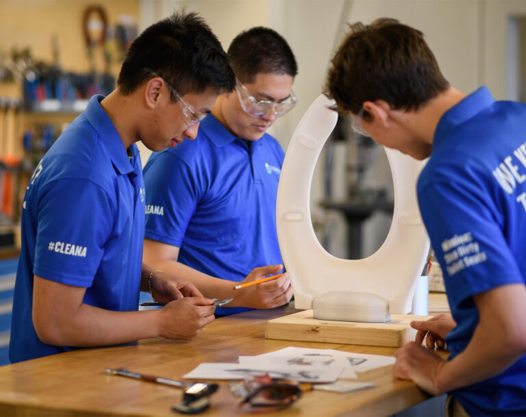 Students working with safety glasses on a project involving a toilet seat