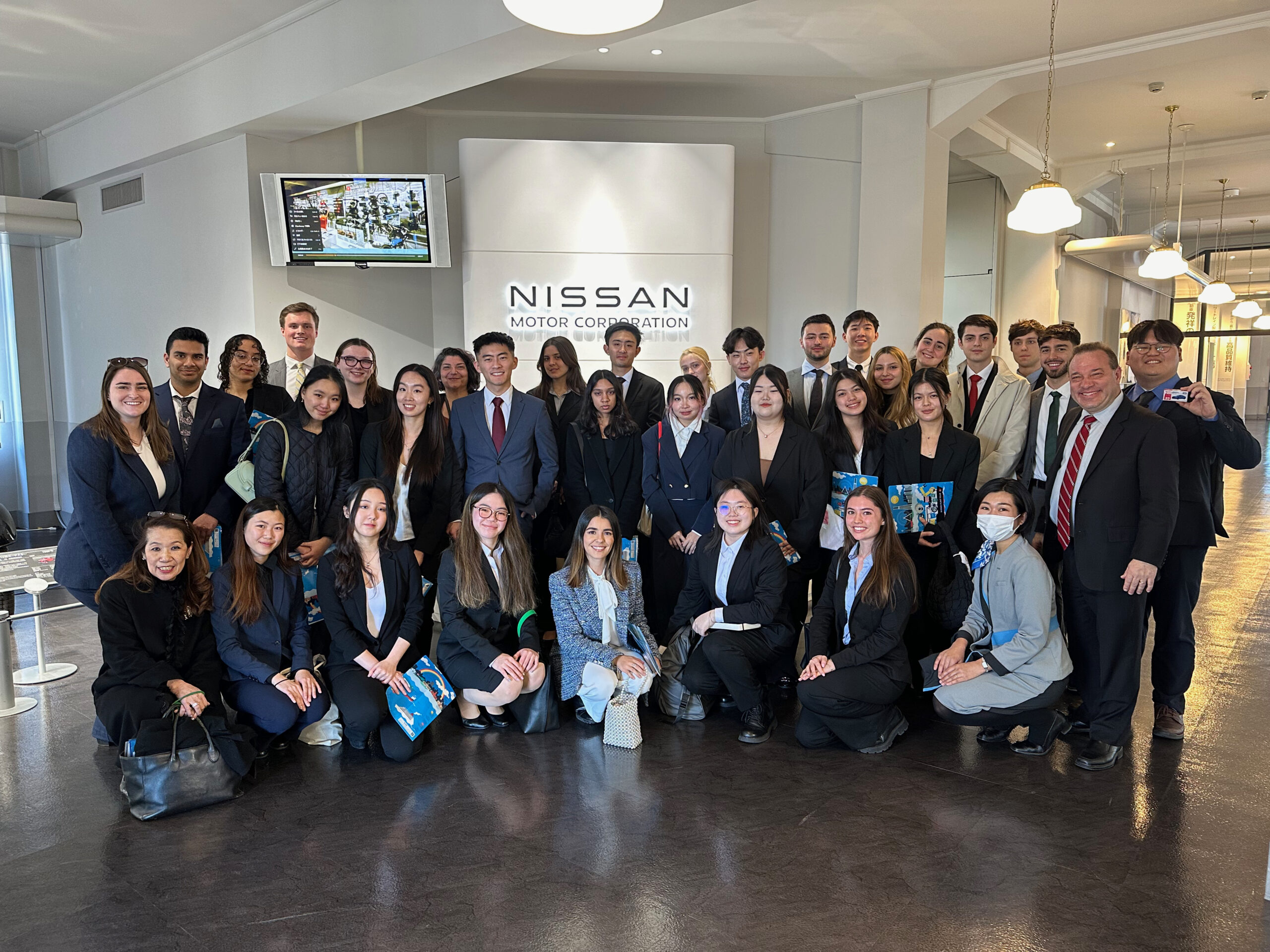 Students pose in front of company logo