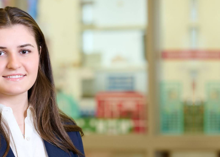Smartly dressed woman student with brown hair and light skin smiles, Farah Baloghlanova
