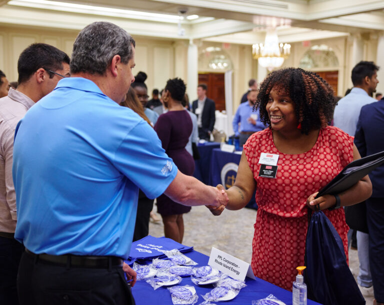 Women shakes hands with an employment recruiter in a room at a career fair.
