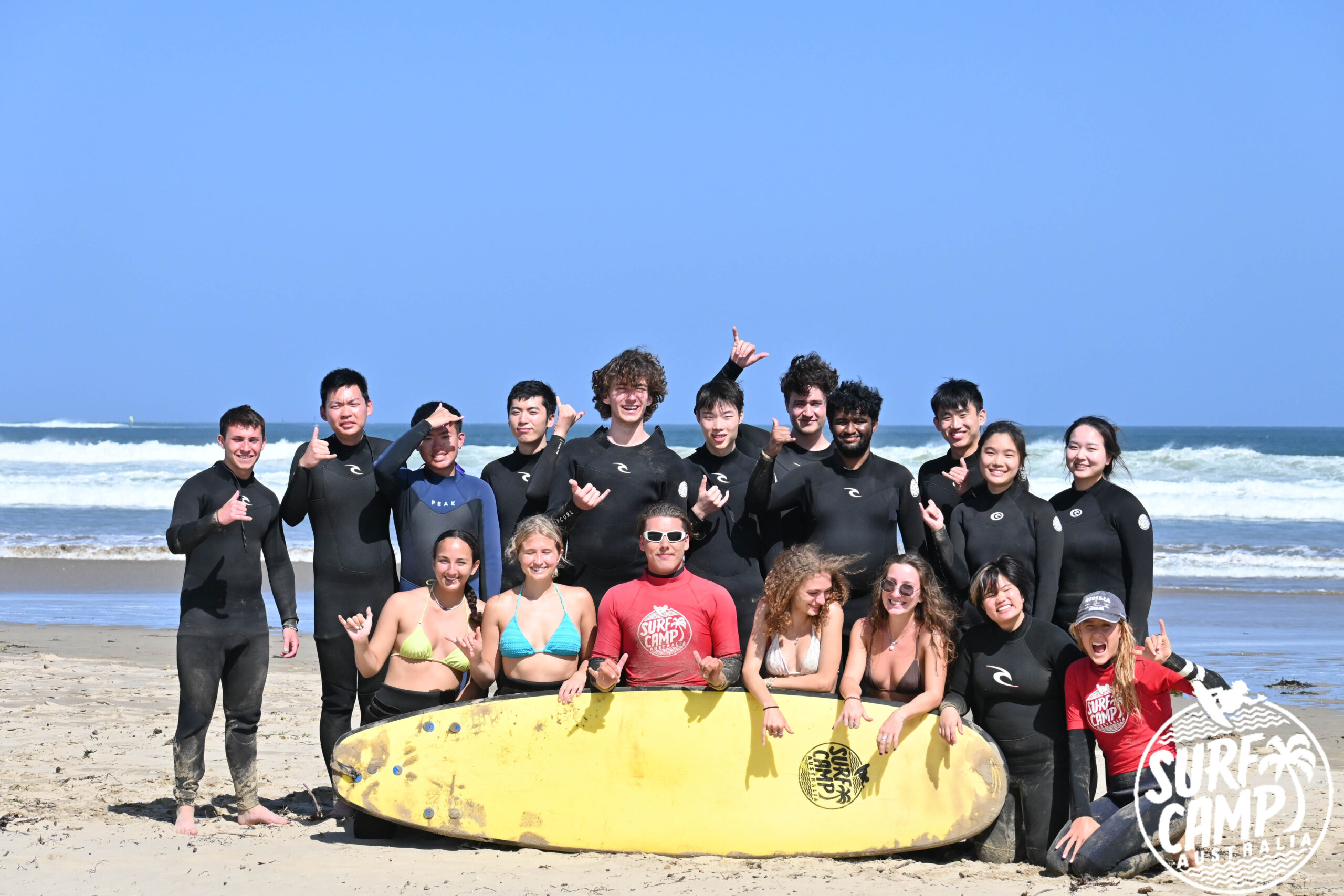 A group photo of students at the beach surfing.