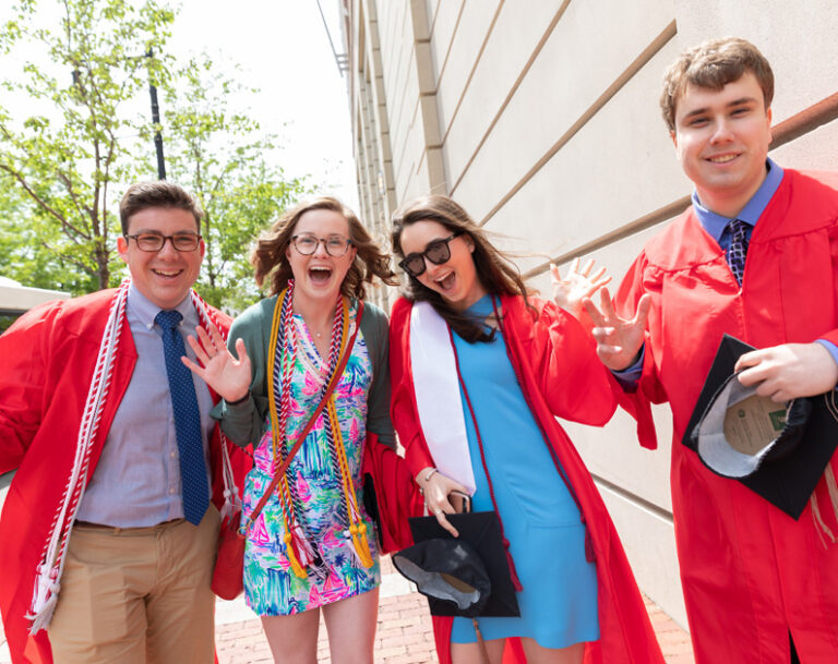 BU Graduates celebrating in red graduation gowns