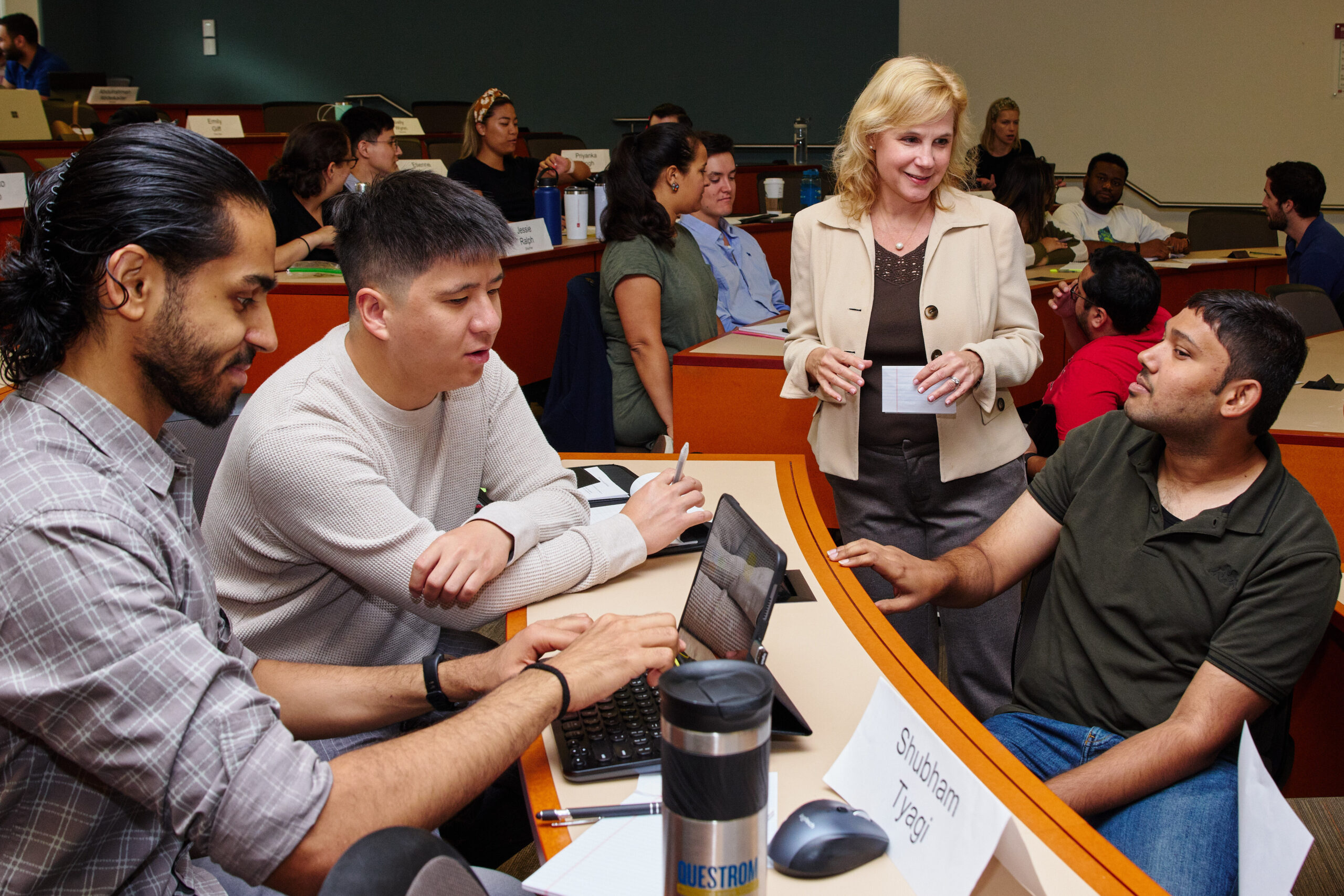 Professor speaking with a group of students in classroom