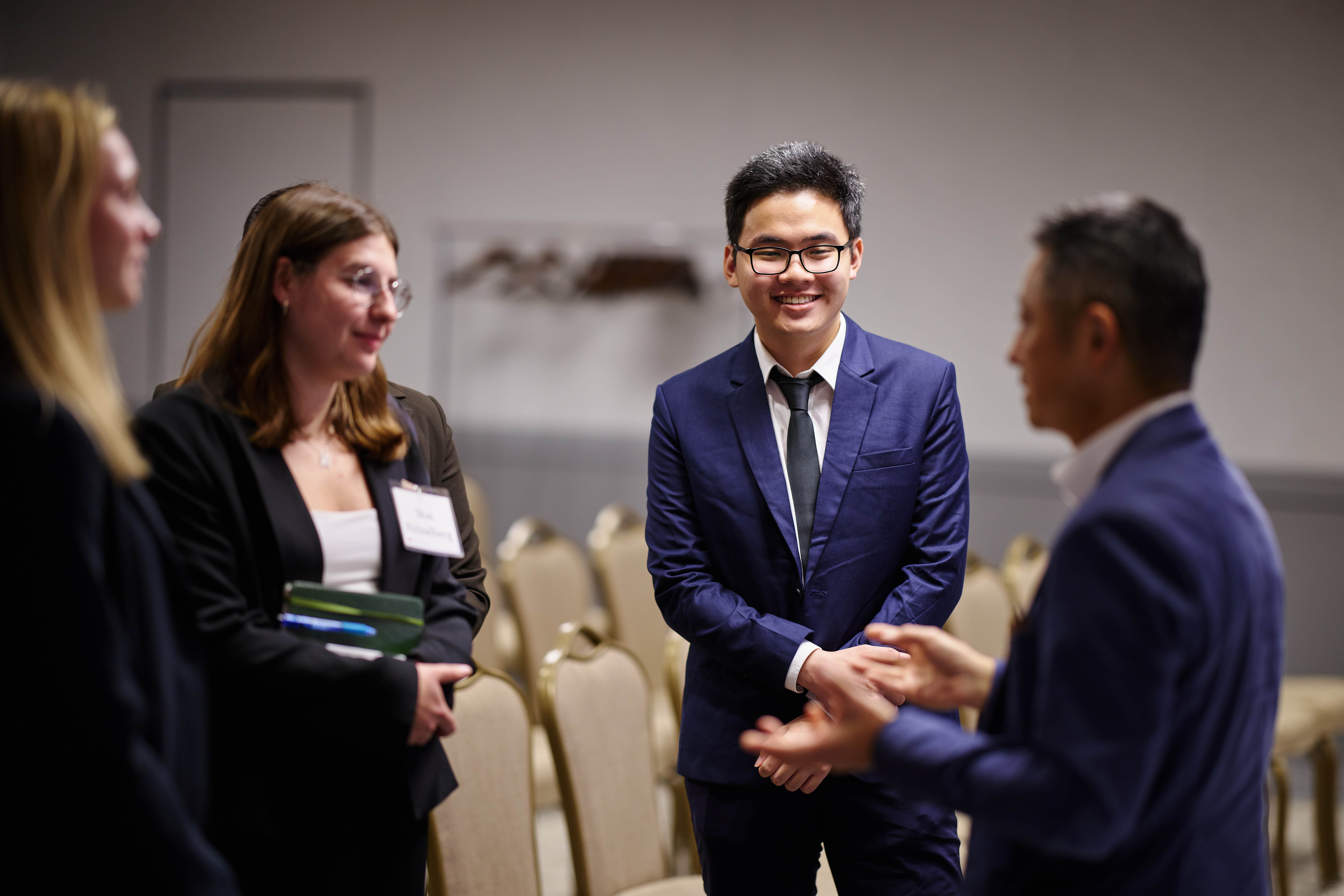 Graduates listening and networking with a guest speaker