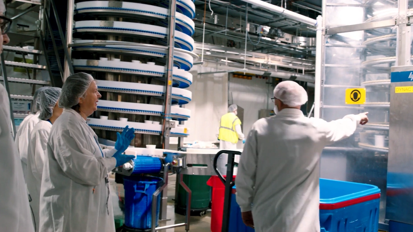 Questrom MBA team learns about machinery in coveralls at a company visit.