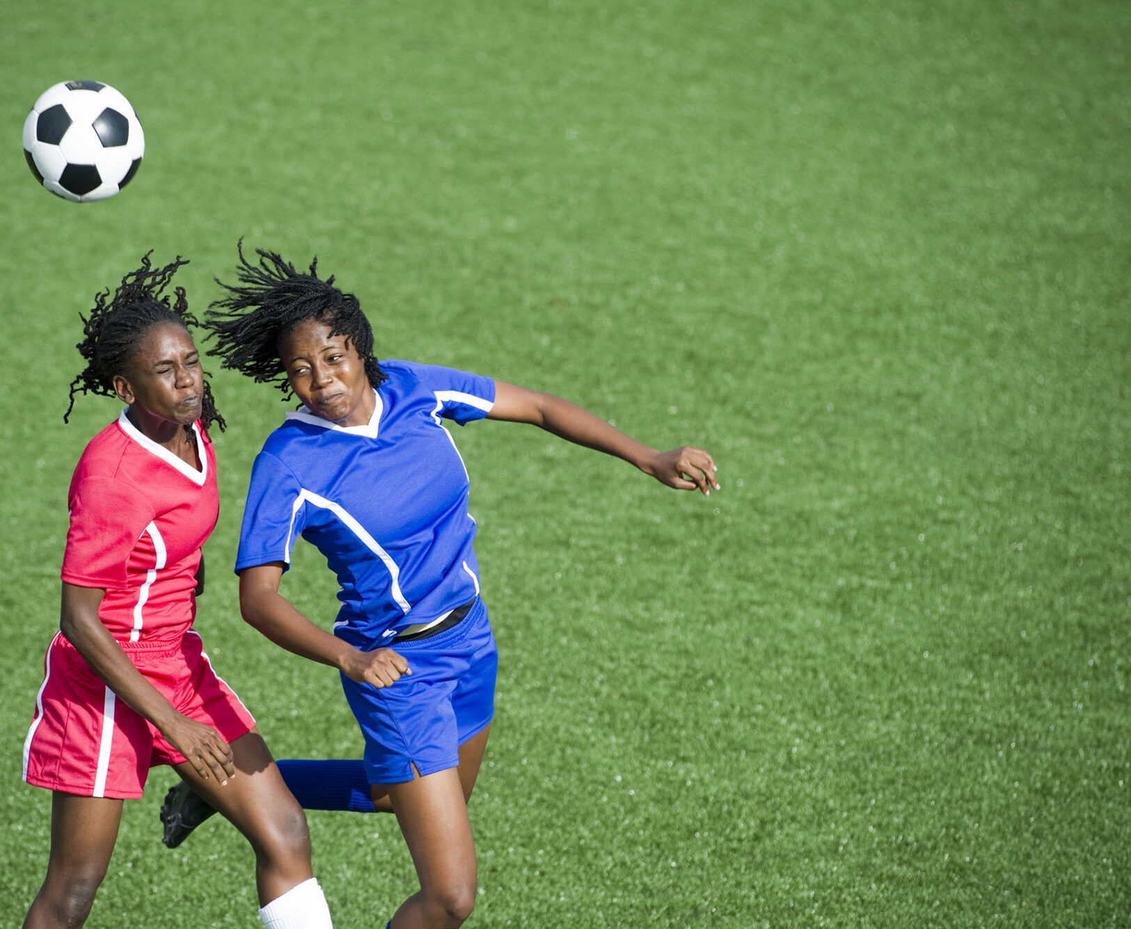Two soccer players passing the ball with their heads