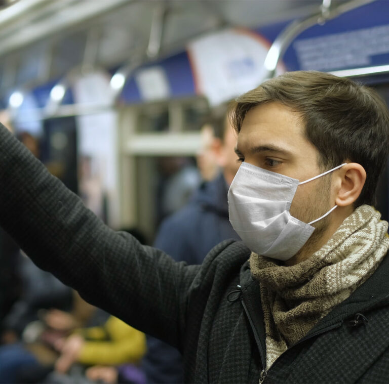 Man standing on subway with a medical mask on