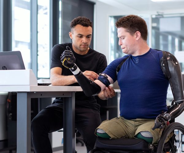 Engineer adjusting arm band on man in wheelchair