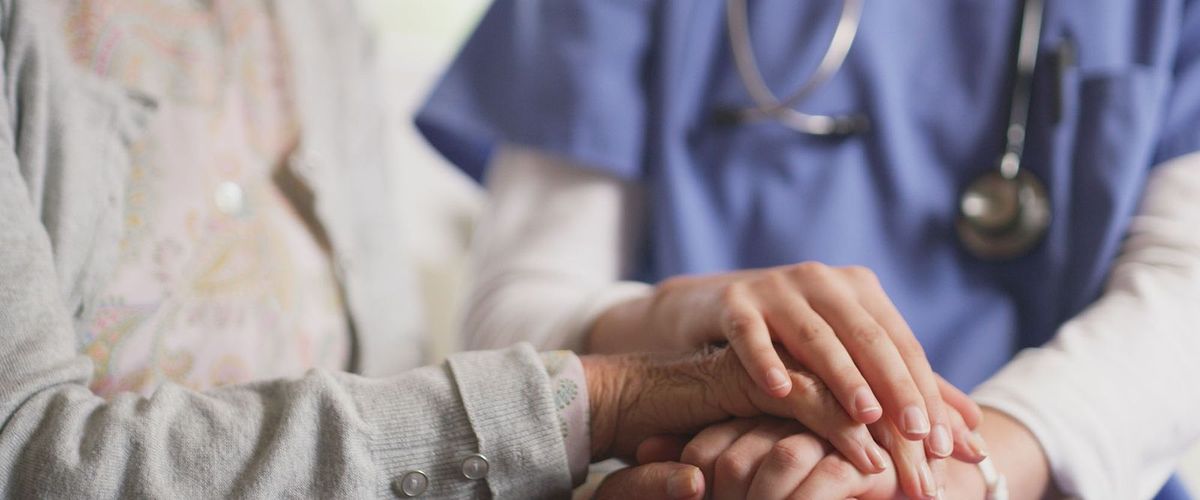 Clasped hands of nurse and elderly patient with Alzheimer's