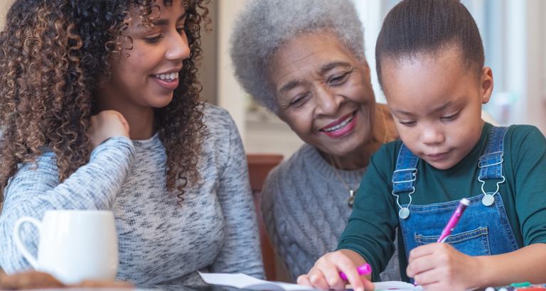 Little child coloring while sitting on grandmother's lap
