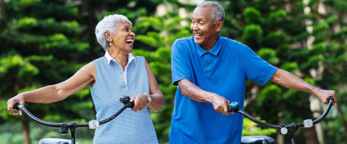 An elderly couple happily rides bikes