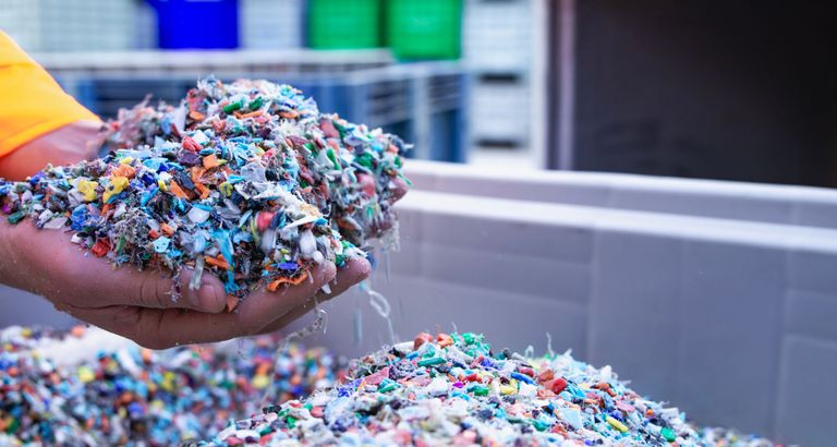 Hands sift through small pieces of plastic waste