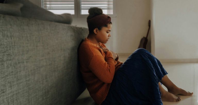 Anxious BIPOC woman sitting on floor