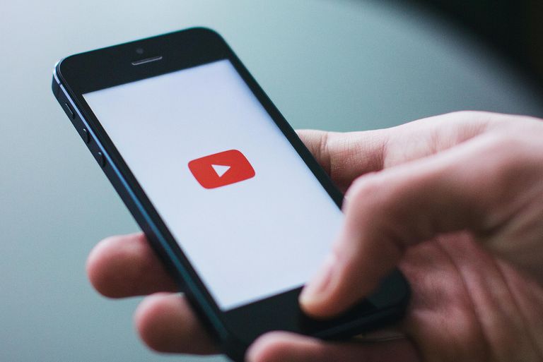 Hand holding smartphone open to video play button