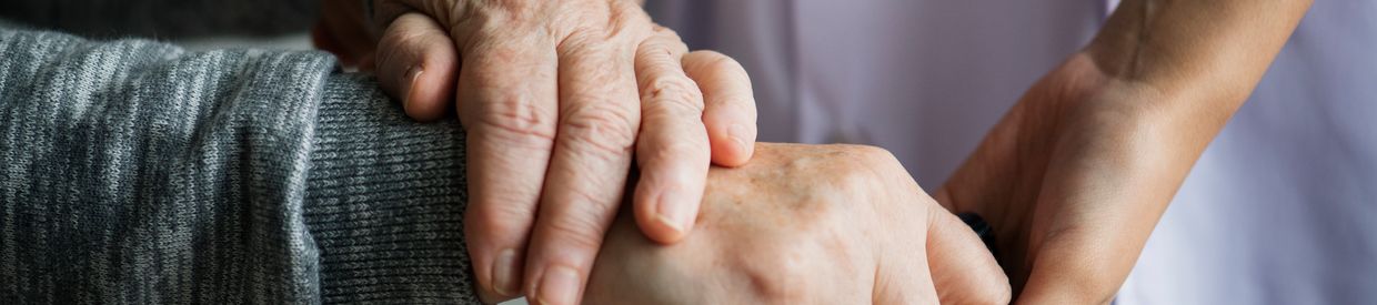 Close-up of hands of caretake and Parkinson's patient with a cane