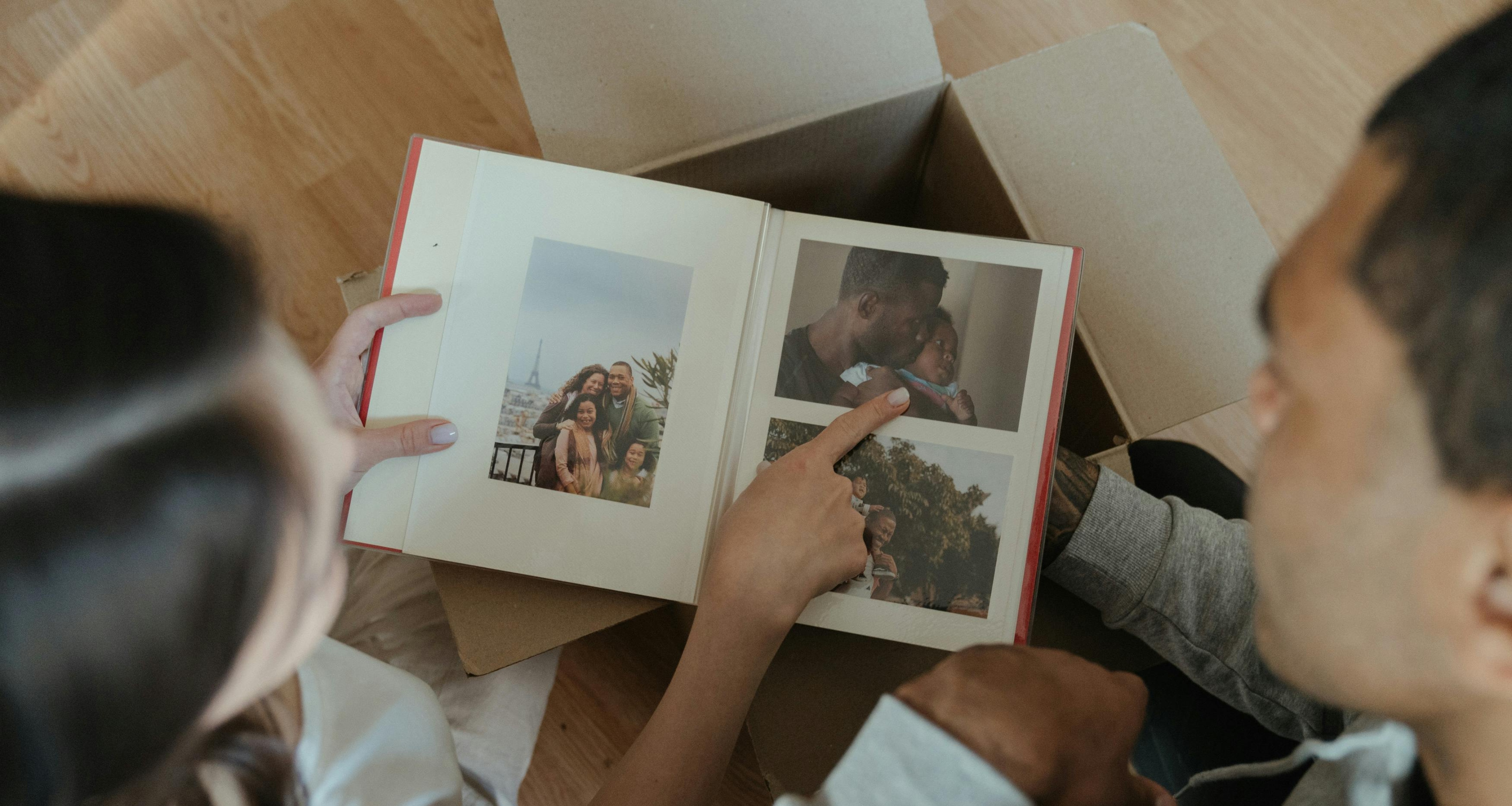 A woman and the man look at a photo album, as the woman points to a photograph