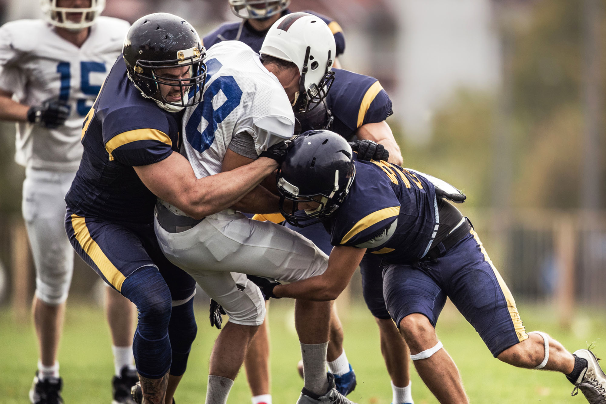 American football players in the middle of a high-impact tackle