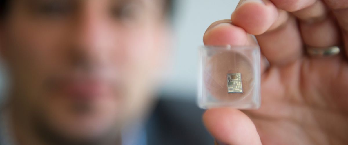 Photonic Integrated Circuit held up in foreground by Jonathan Klamkin in blurry background