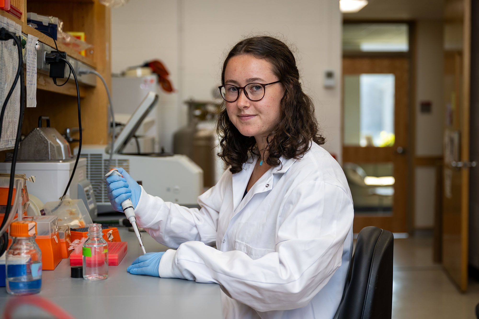 Young female researcher sitting at a lab desk filling test tubes