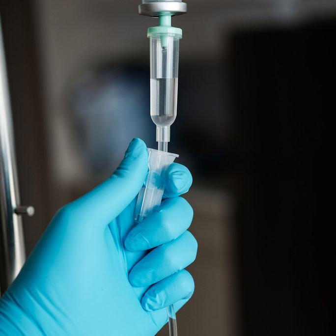Hand in a blue medical glove administering chemotherapy in close-up
