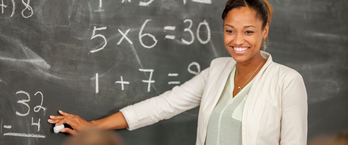 Teacher standing at blackboard teaching math