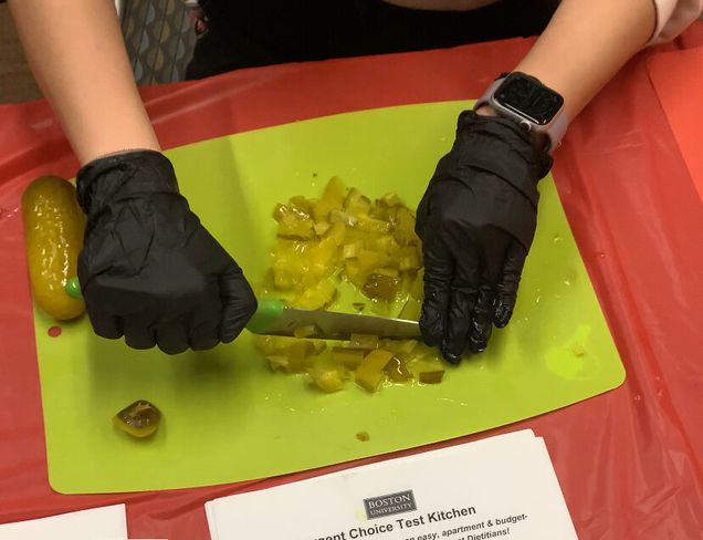 To show the process of finely chopping the dill pickles.