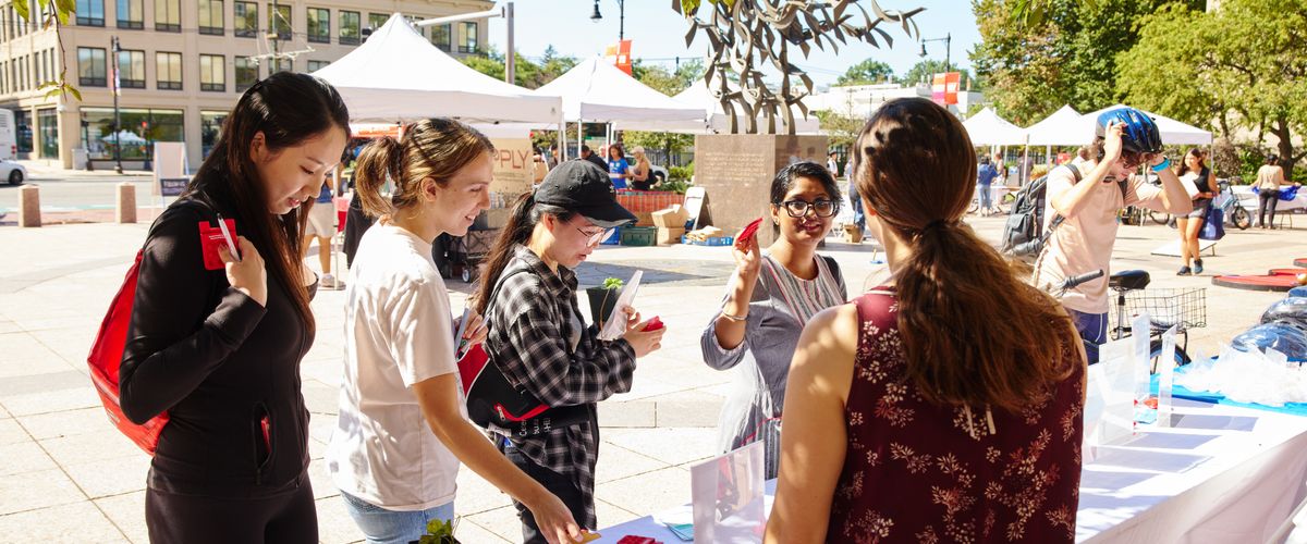 Students conversing with an SHS staff at a tabling event outside