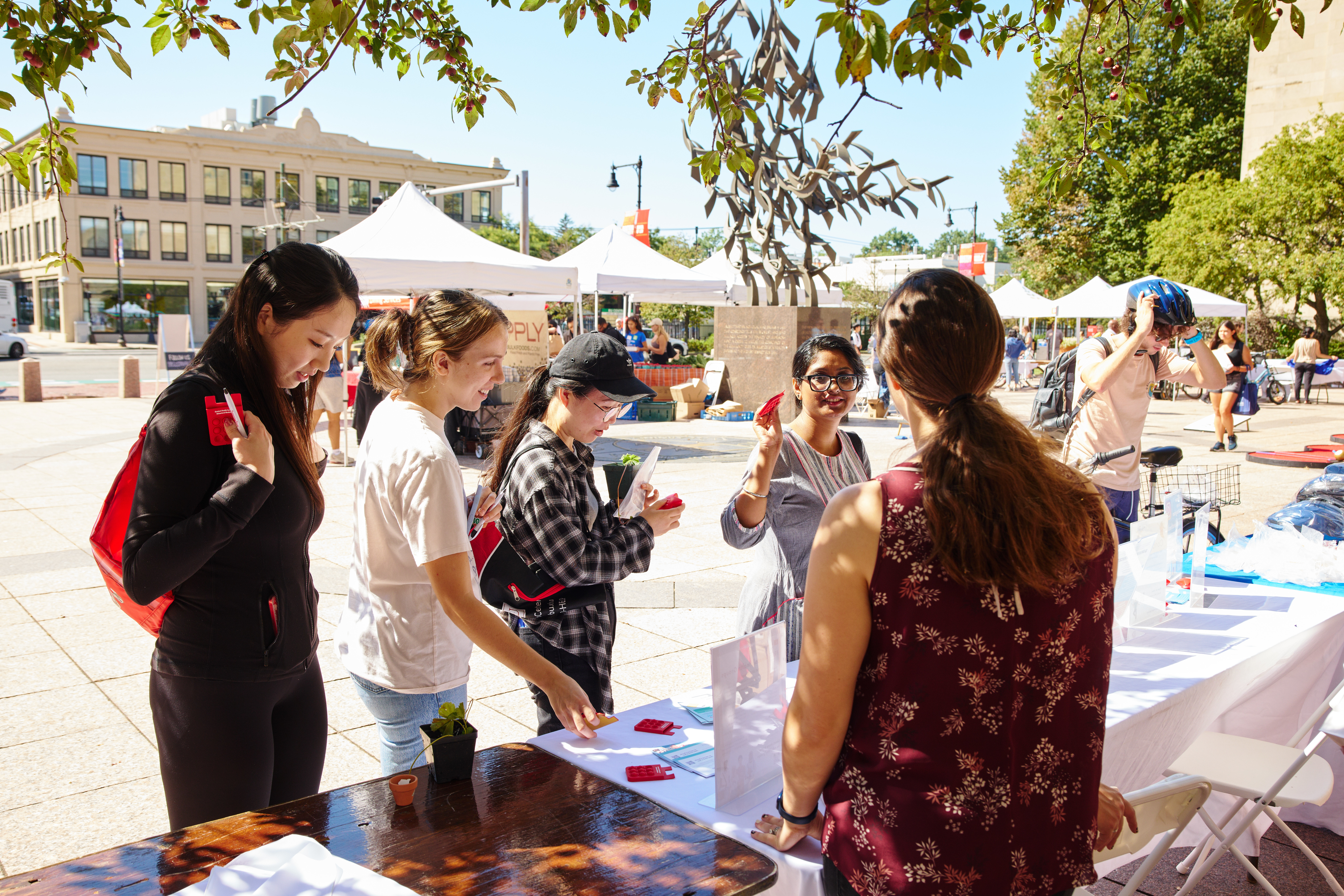 Students conversing with an SHS staff at a tabling event outside