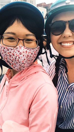 Lindsay White (right) gets a motorbike ride from a colleague on the way to Hanoi Medical University.