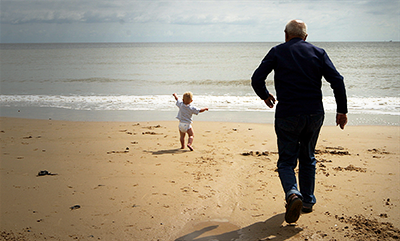 elderly-man-chasing-toddler-on-beach