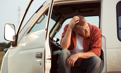 Man sitting in pulled-over truck with head in hands