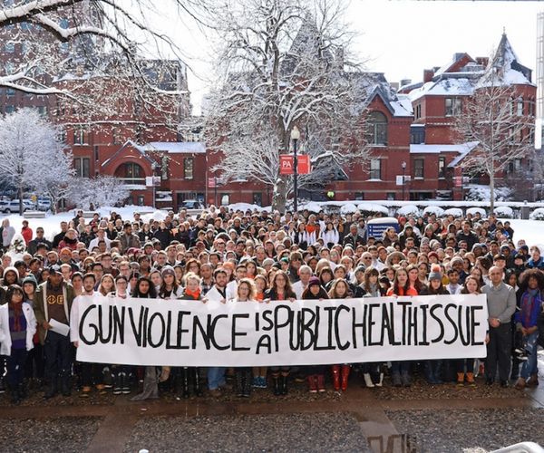 BU Medical Campus walk-out for gun violence; crowd stands in front of SPH's Talbot Building in the snow, holding a banner that reads "Gun VIolence Is a Public Health Issue"