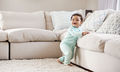 Toddler leaning against sofa