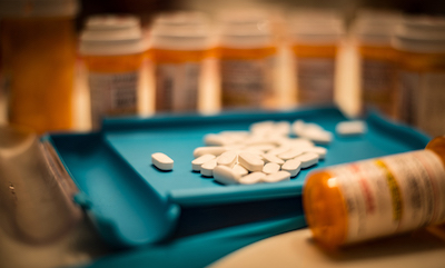 Unsorted prescription pills sit in a pharmacist's counting tray before they are bottled.