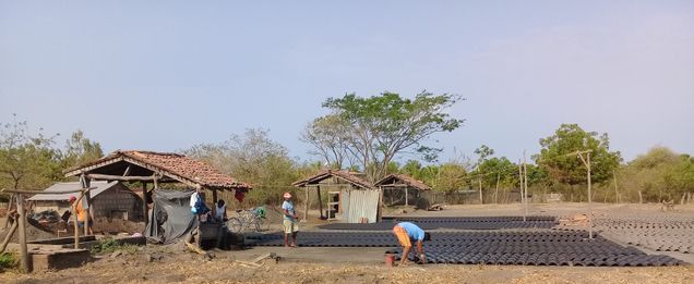 Men at the brickworks lay out roof tiles on the ground.