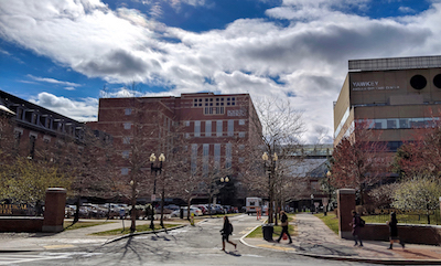 View of Boston Medical Center's Moakley Pavilion and Yawkey Ambulatory Center, with a car pulling into the drop-op area in the foreground and "Boston Medical Center" written on metal fences on the left and right.