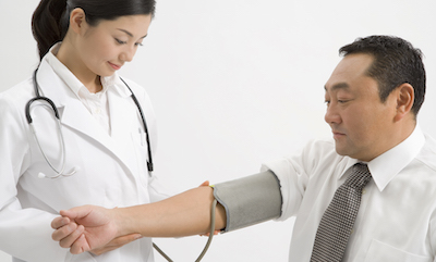 Female Japanese doctor takes blood pressure of middle-aged Japanese man