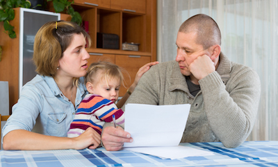 Worried family with child sitting with financial documents at home