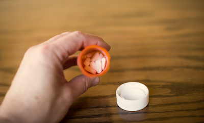 Close-up of oblong pink pills in a pill bottle.