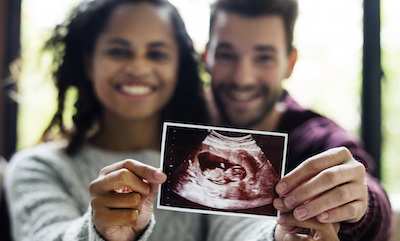 Excited parents-to-be holding up a sonogram