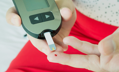 Close-up of hands of Thai woman measuring glucose