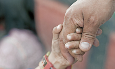 Farmworker's hand holding hand of child