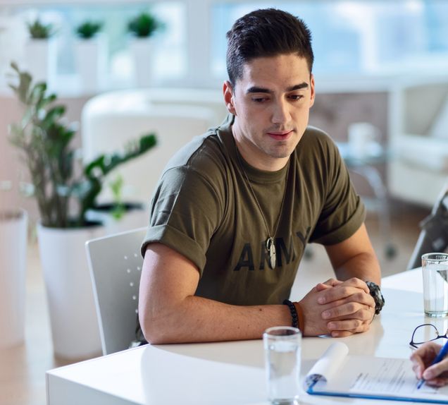 Young sad military officer sitting at doctor's office during his psychotherapy.