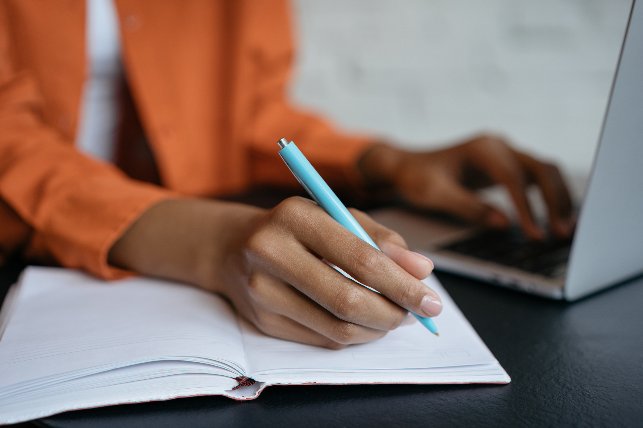 Close-up shot of student hand holding pen and writing in notebook