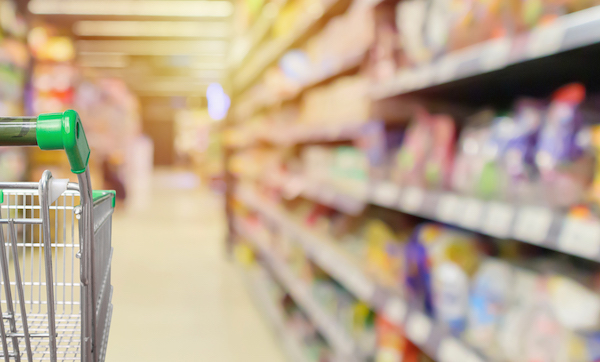 shopping cart in supermarket aisle with product shelves interior defocused blur background
