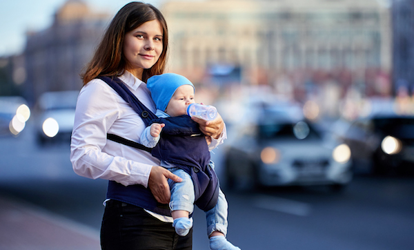 Young mother uses baby sling for an outdoor walk with her child.