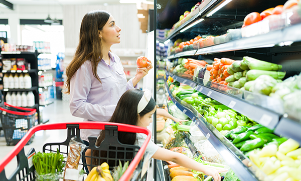 Woman and child pick vegetables from the grocery store