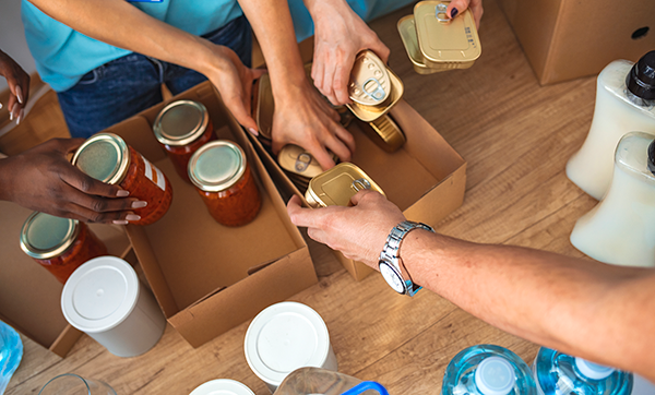 Hands pack non perishable food into cardboard boxes